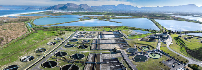 Panoramic aerial view of an industrial waste water treatment plant with circular clarifier tanks,...