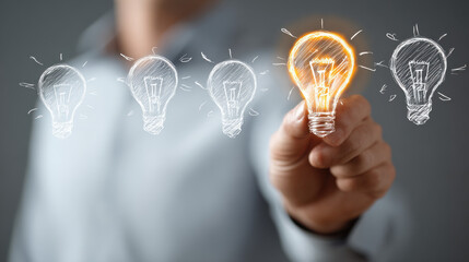 Person holding bright glowing light bulb among faded bulbs showing idea leadership innovation and inspiration for startup business success