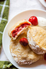 Close-up of vareniki with strawberries and cream on a white plate. Great for cookbooks, recipe cards, and advertising Eastern European cuisine.