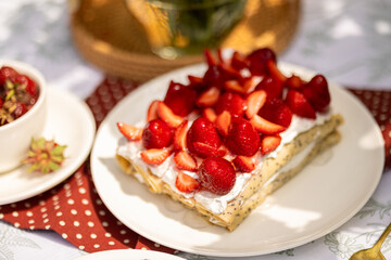 Elegant summer dessert: strawberry crepe cake with poppy seeds. Laid-back picnic in natural garden light.