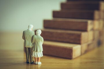 Old senior couple looking at high staircase. Aging society problem and prepare for retirement such as financial planning, healthcare costs, mental health, elder care burdens, social isolation concept.