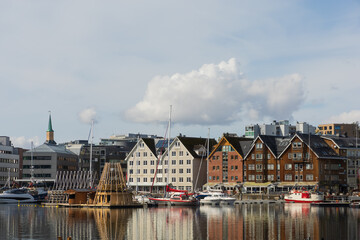  Scenic harbor of Tromsø, Norway with colorful wooden houses, yachts, and reflections in the water.
