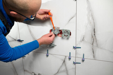 Crop view of electrician checking electric socket in new bathroom. Power socket installation....