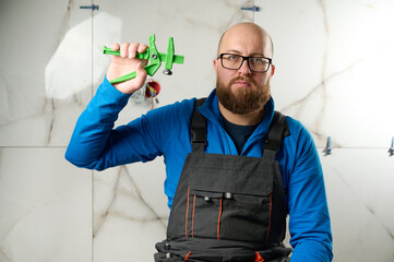 Man installing ceramic granite tiles on the wall in the new apartment. Plumber installing ceramic...