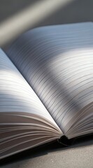 Open notebook with lined pages, sunlight illuminating the pages, showing texture and subtle shadows