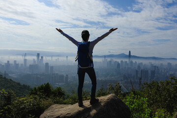 Woman hiker stand on the mountain top rock looking at the beautiful view