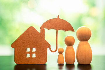 Model of umbrella with house and family on wooden table Security protection and health insurance. The concept of family home, protection, health care day