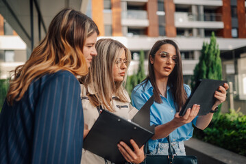 Businesswomen using tablet and clipboard discussing a project outdoors