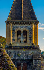 Detail of the historic tower of the Abbey Church of Sainte-Foy in Conques, France, illuminated by the golden light of sunset.