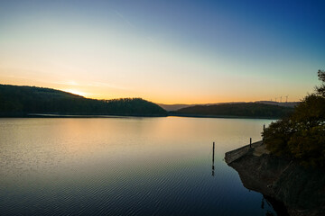 View of the Rursee at the dam near Heimbach-Schwammenauel. Landscape at the lake at sunset. Nature in the Eifel National Park.
