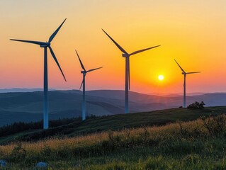 Obraz premium Wind turbines stand tall against a vibrant sunset, casting long shadows over rolling hills. The sky transitions from orange to purple, highlighting the peaceful energy generation in nature.