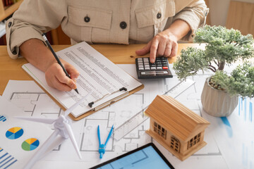 Engineer is analyzing costs for a sustainable building project, incorporating renewable energy solutions like wind turbines, focusing on ecological design and innovation