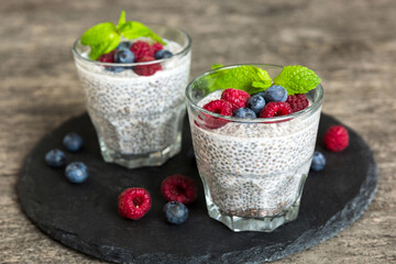 Healthy breakfast or morning with chia seeds vanilla pudding raspberry and blueberry berries on table background, vegetarian food, diet and health concept. Chia pudding with raspberry and blueberry