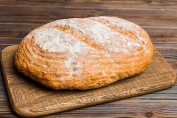 Freshly baked bread on cutting board against white wooden background. perspective view bread with...