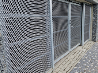 yard for placing containers for sorting household waste. gray door and halving of perforated metal...