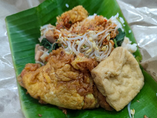 A portion of typical Indonesian pecel served on banana leaves, consisting of white rice, boiled...