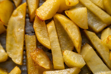 Homemade golden potato wedges baked in the oven, close-up