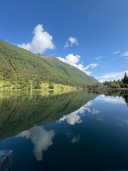 Naklejka premium Tranquil alpine landscape with the deep blue sky reflected in a serene mountain lake, surrounded by snow-capped peaks