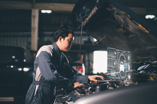A mechanic wearing a jumpsuit diagnoses a car engine with digital holographic interface technology in a dimly-lit garage.