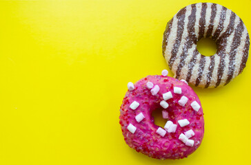 two donuts on yellow background, sweet donuts background, chocolate donut and pink donut with...