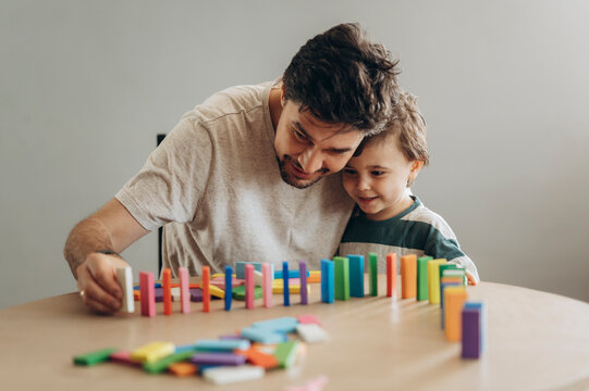 Father and son playing with colorful dominoes at home