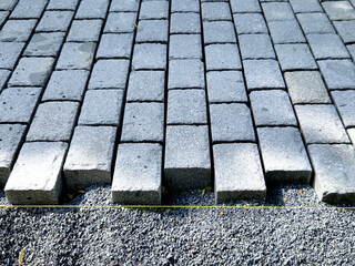 laying paving stones made of precisely cut granite blocks on the street. leveling the surface using...