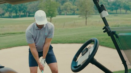A male golfer hits an iron off the fairway in slow motion. The shot is framed from a partner POV angle through a golf cart, creating a unique, immersive view of the swing and impact. - Powered by Adobe