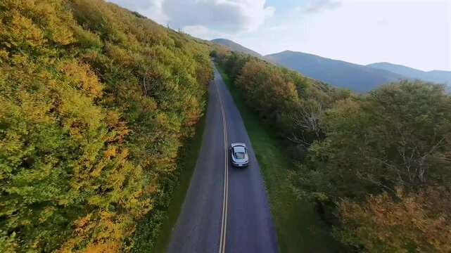 Aerial Following grey Sports Car in Blue Ridge Parkway mountains, with cloudy sky US National Park