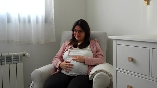 Young pregnant woman crying excited about her future baby on a rocking chair at home
