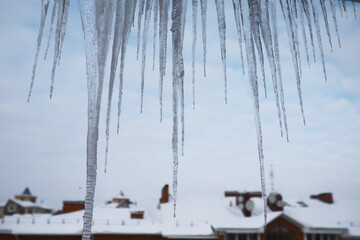 Icicles Hanging From Roof Over Snow-Covered Town on a Winter Day