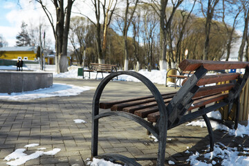 Snowy Park Bench in Winter with Scenic Background and Bare Trees