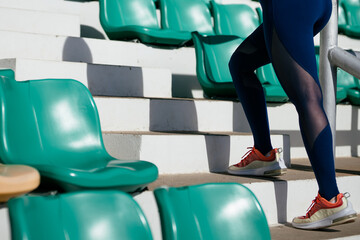 Close-up of a woman in athletic shoes walking up the stairs of the stands inside a stadium