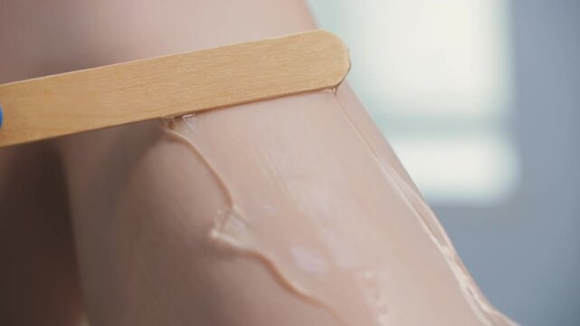 Applying gel to leg with wooden spatula
