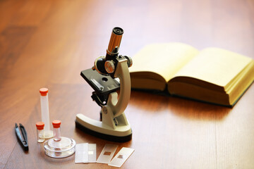 Microscope and Open Book on Wooden Desk for Science Research and Study