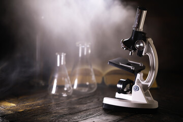 Vintage Microscope and Laboratory Glassware on Wooden Table with Dramatic Lighting
