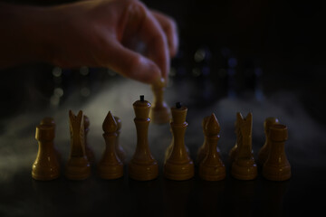 Hand Placing Chess Piece on Board in Mysterious Dim Lighting for Strategic Gameplay