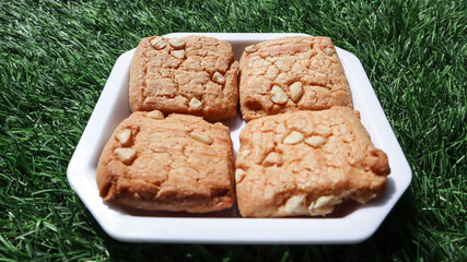 Closeup of yummy baked dry fruit cookies served on plate with green grass nature background