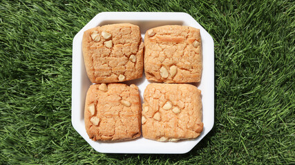 Top view of yummy baked dry fruit cookies served on plate with green grass nature background