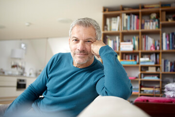 Man relaxing at home in a cozy living room with a bookshelf in the background