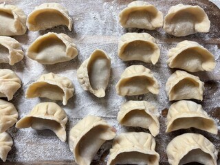Homemade Handmade Dumplings on Wooden Cutting Board – Flour-Sprinkled Rustic Scene for Healthy Cooking & Preserves