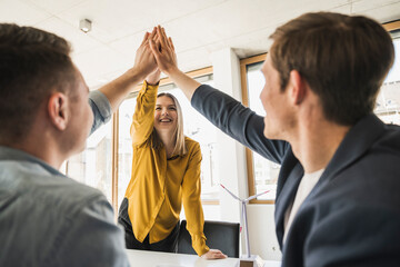 Happy business team high fiving in office