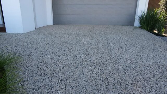 Modern concrete exposed aggregate driveway in front of a suburban home garage in Australia. Clean, durable surface ideal for residential curb appeal and low-maintenance landscaping.