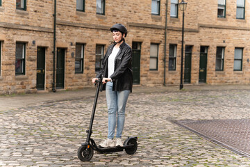 Woman riding an electric scooter on cobblestone street in historic urban setting during daytime...