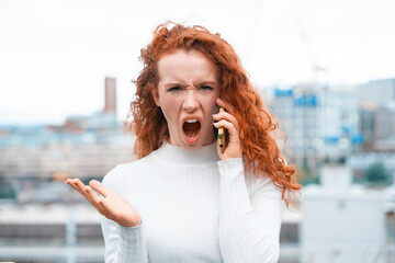 Woman expressing frustration during phone call in urban setting on a cloudy day