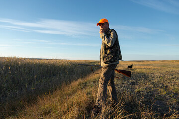 Mature man hunter with gun while walking on field.