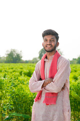 young indian farmer standing at green agricultural field
