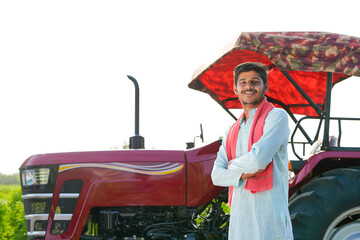 young indian farmer standing with tractor at field