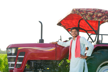 young indian farmer standing with tractor at field