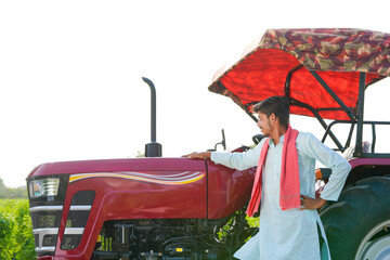 young indian farmer standing with tractor at field
