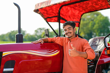 indian farmer standing with tractor at field